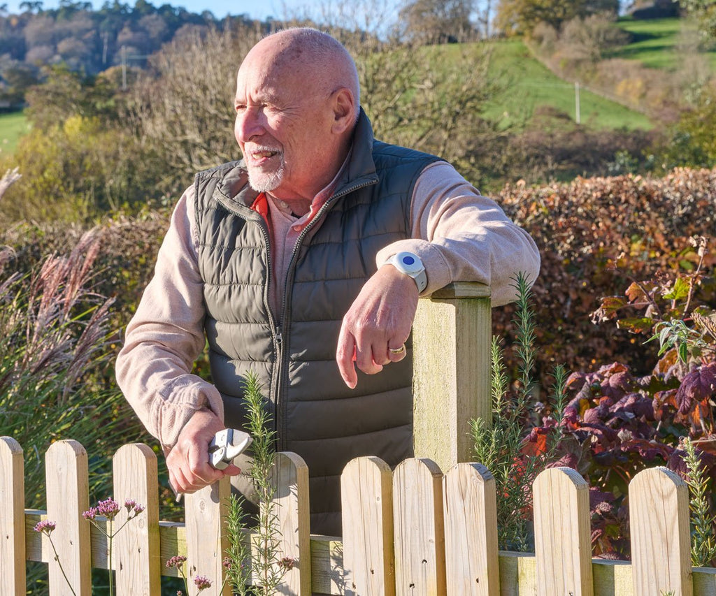 Man standing outdoors near a wooden fence with a scenic background