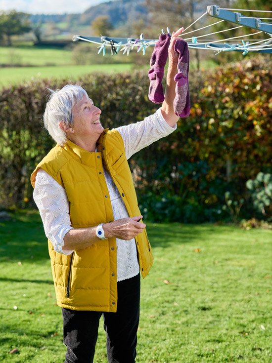 Lady hanging the washing out wearing a call button wrist alarm