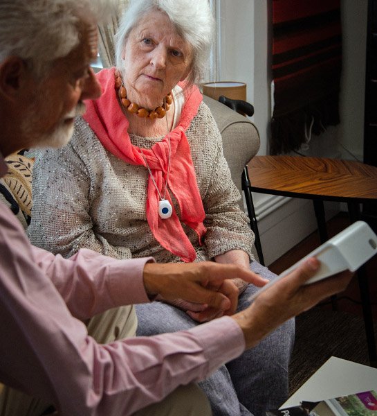 Two elderly women sitting together, one showing base unit