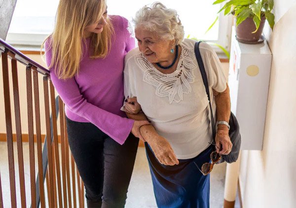 Daughter helping elderly mother up the stairs