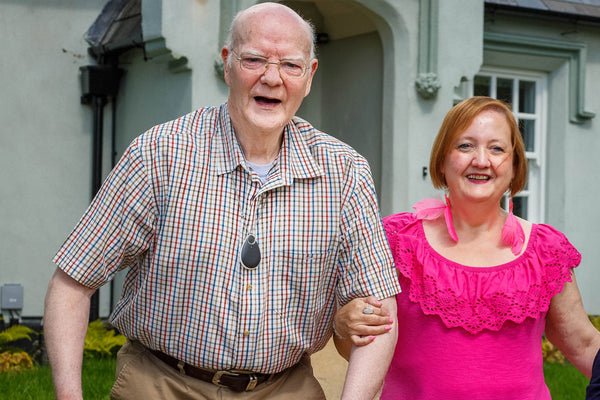 Two people standing outdoors in front of a house