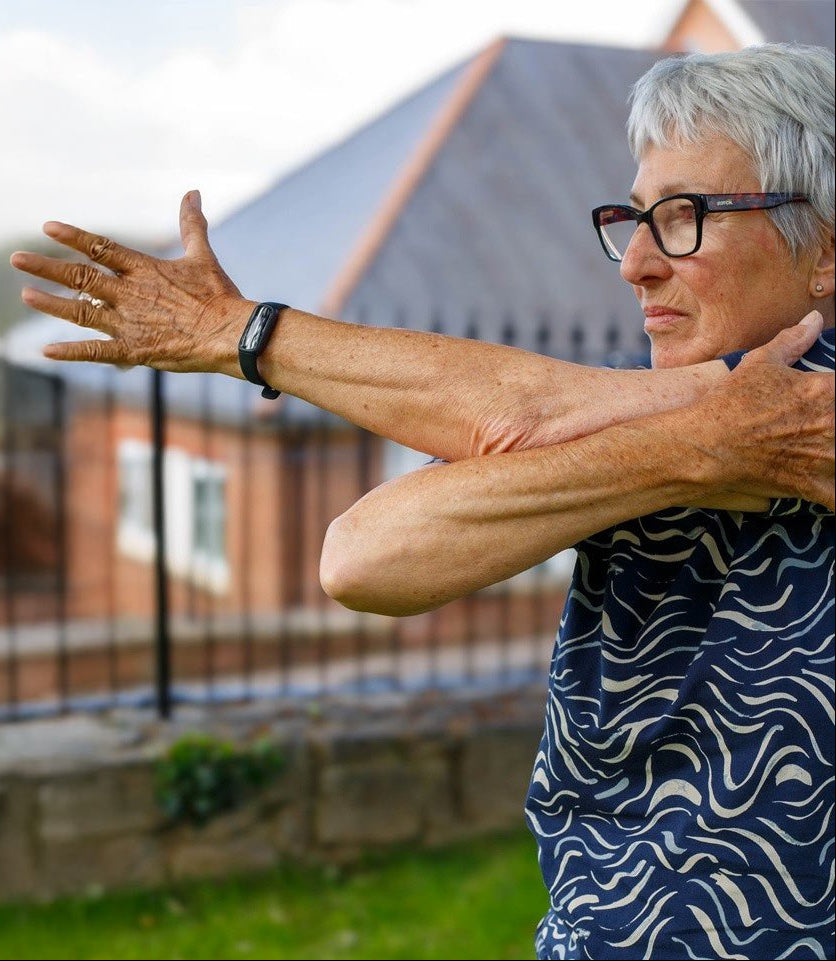 Senior woman stretching outdoors with a house in the background