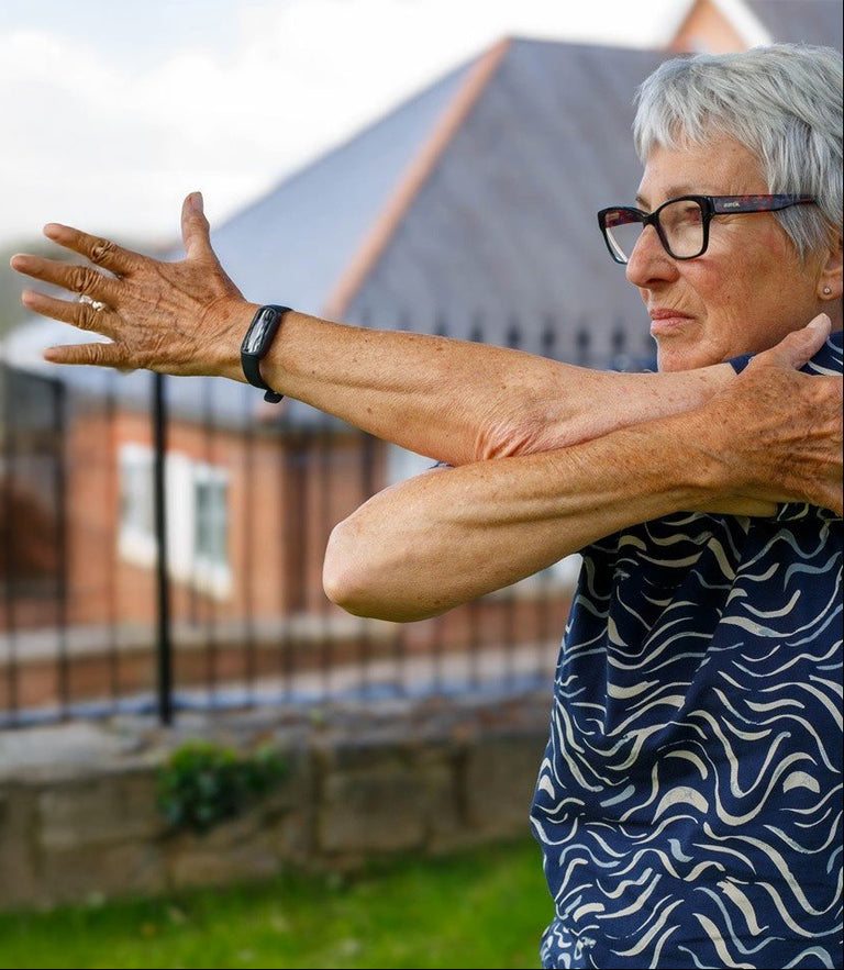 Senior woman stretching outdoors with a house in the background