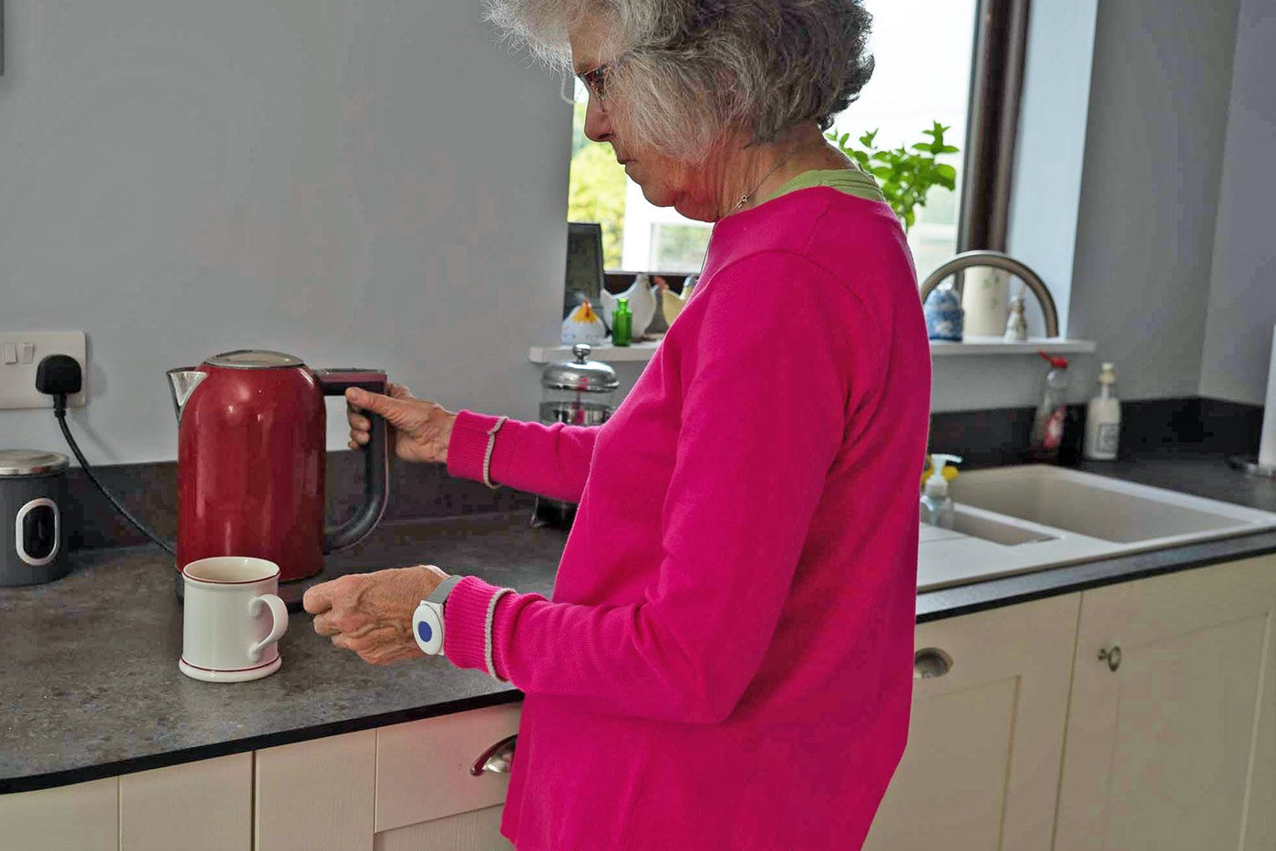 Older lady in kitchen wearing wrist worn fall alarm