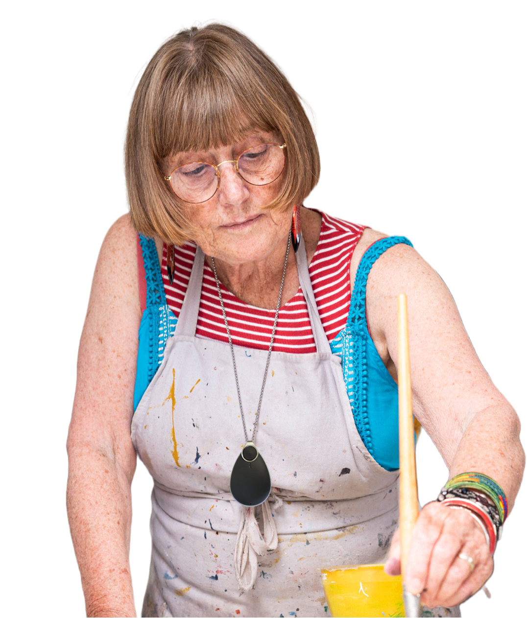 Elderly woman painting, wearing a black personal alarm around her neck.