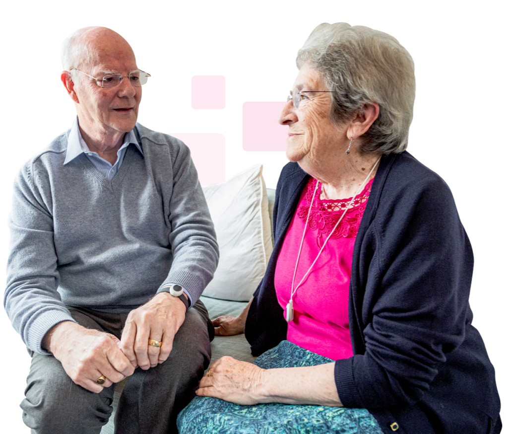 Elderly couple sat on sofa and talking.